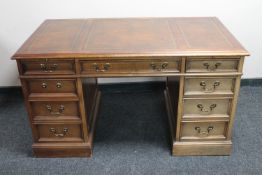 A mahogany twin pedestal writing desk inset three tooled brown leather panels