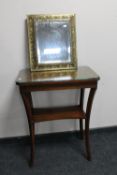 An embossed brass cushion mirror and a two tier occasional table