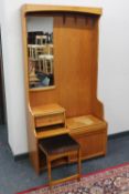 A late 20th century teak hall stand fitted cupboard beneath and a slide out stool