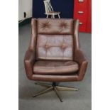 A mid 20th century Danish brown button leather swivel armchair on metal base and similar footstool