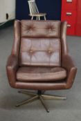 A mid 20th century Danish brown button leather swivel armchair on metal base and similar footstool