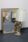 A chalk cherub table lamp and a gilt framed mirror