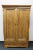 A pine double door hanging wardrobe fitted a drawer