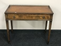 A Regency style writing table with brown tooled leather inset panel and a brass gallery