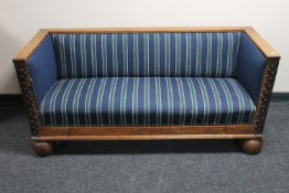 An antique oak framed hall settee on bulbous feet with metal mounts and fittings