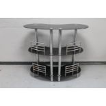 A contemporary black glass and metal three tier bar