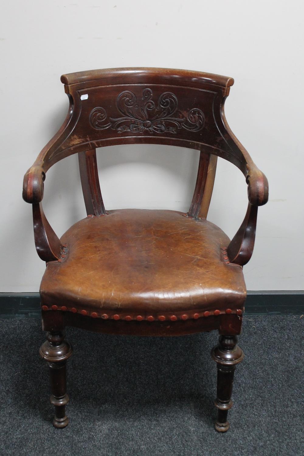 An antique carved mahogany office armchair in brown leather