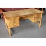 A blonde oak writing desk fitted six drawers