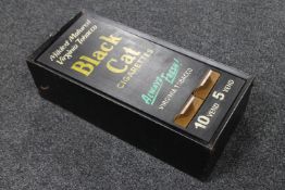 A metal cigarette dispenser bearing Black Cats Cigarette advertising