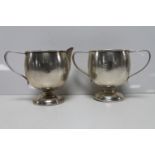 A white metal sugar basin and milk jug,