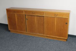 A mid 20th century teak sliding door bookcase fitted three drawers above CONDITION