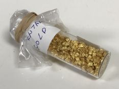 A glass bottle of 24ct dental gold, weighing 2.