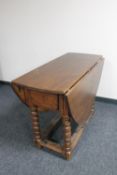 An antique oak gate leg table on bobbin turned legs