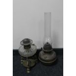 An antique brass Veritas oil lamp with glass chimney and a further glass reservoir oil lamp on a