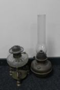 An antique brass Veritas oil lamp with glass chimney and a further glass reservoir oil lamp on a