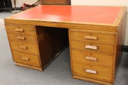 An early twentieth century oak twin pedestal desk fitted with eight drawers