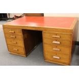 An early twentieth century oak twin pedestal desk fitted with eight drawers
