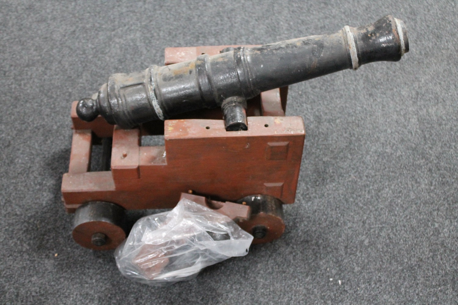 A replica metal ship's cannon on wooden trolley and a bag of nine replica cannon balls