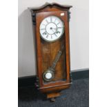 An antique walnut cased eight day wall clock with enamelled dial and pendulum