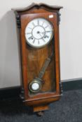 An antique walnut cased eight day wall clock with enamelled dial and pendulum