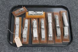 A tray of nine metal train models on wooden stands