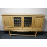 A blonde oak four door sideboard with leaded glass doors