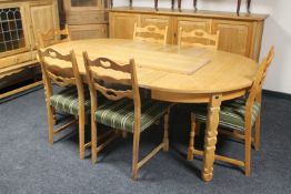A circular blonde oak extending table with three leaves and six ladder back chairs