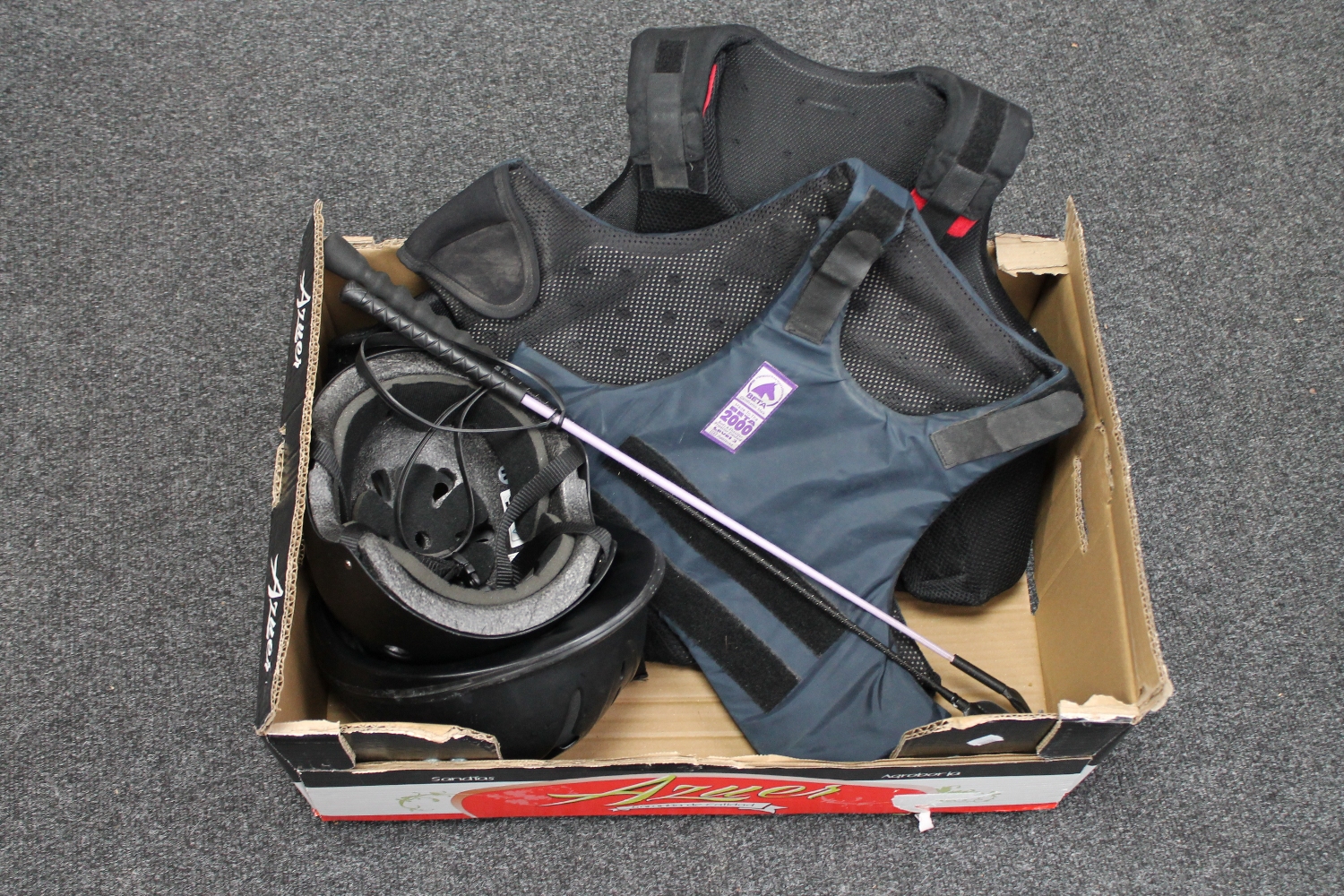 A box of horse riding equipment - two riding hats,