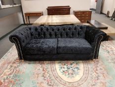 A contemporary Chesterfield style settee in plush black fabric,