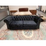 A contemporary Chesterfield style settee in plush black fabric,