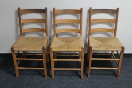 A set of three pine ladder back rush seated kitchen chairs