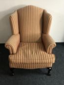 A wingback armchair on claw and ball feet upholstered in a red and gold striped print