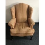 A wingback armchair on claw and ball feet upholstered in a red and gold striped print