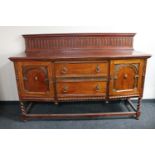 A late Victorian carved oak rail back sideboard on barley twist legs