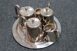 A circular silver plated tray containing a five piece plated tea and coffee service