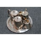 A circular silver plated tray containing a five piece plated tea and coffee service