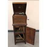 An oak cased HMV gramophone on cabinet containing a quantity of 78's