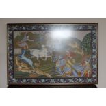 A framed wool work panel depicting Indian hunters on horseback