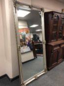 An ornate silvered leaning mirror,