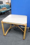 A square marble topped table on a bamboo base