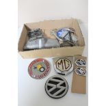 A box of a collection of vintage car badges with fittings