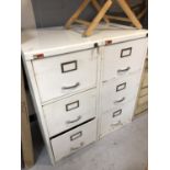 A pair of three drawer white metal filing cabinets