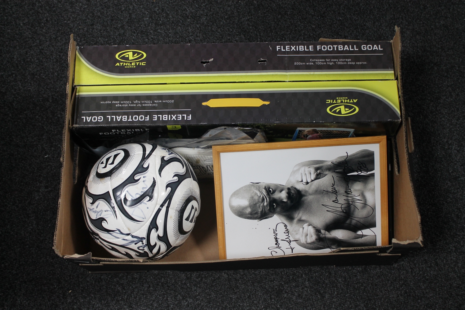 A box of two boxed flexible football goals, signed football,