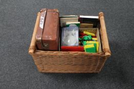 A wicker basket, a vintage luggage case containing drawing instruments, children's building blocks,