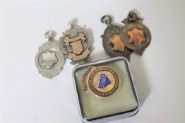 Four 20th century silver sports medals together with a silver and enamelled badge,