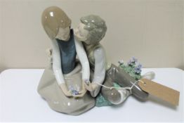 A Lladro figure of young lovers seated with flowers