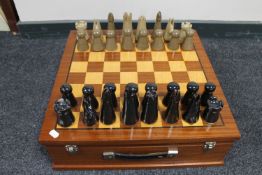 A teak storage box with chessboard top containing a set of pottery chess pieces