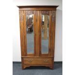 An Edwardian mahogany double door mirrored wardrobe fitted a drawer beneath