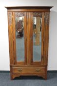 An Edwardian mahogany double door mirrored wardrobe fitted a drawer beneath