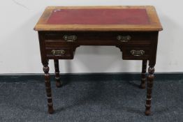 An Edwardian mahogany three drawer writing table with a red leather inset panel